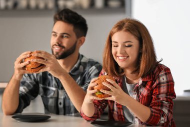 Genç çift evde lezzetli hamburger yemek