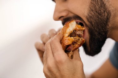Lezzetli burger yiyen genç adam, yakın plan.
