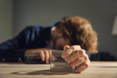 Masada şişe ve boş camla baygın sarhoş bir adam. Alkolizm kavramı
