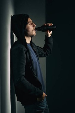 Depresif genç adam karanlık odada bira içiyor. Alkolizm kavramı