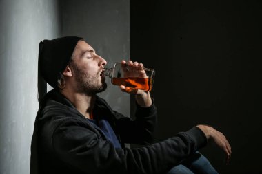Depresif genç adam karanlık odada viski içiyor. Alkolizm kavramı