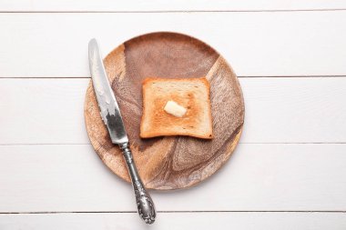 Beyaz ahşap masa üzerinde kızarmış ekmek ve tereyağı ile plaka