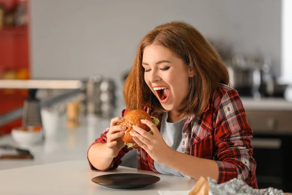 Jovem Mulher Comendo Hambúrguer Saboroso Casa — Fotografia de Stock