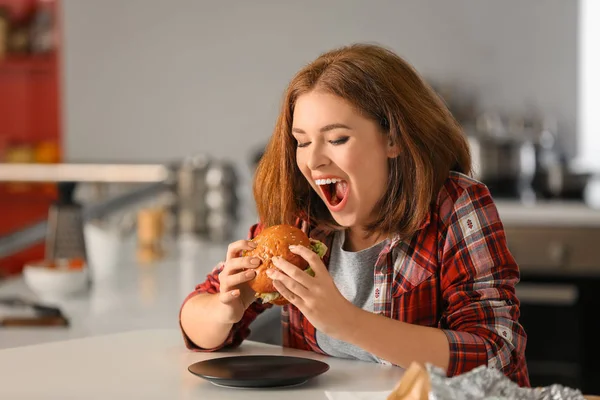 Young Woman Eating Tasty Burger Home — Stock Photo, Image