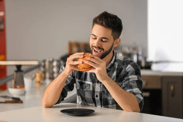 Νεαρός Άνδρας Τρώει Νόστιμο Burger Στο Σπίτι — Φωτογραφία Αρχείου