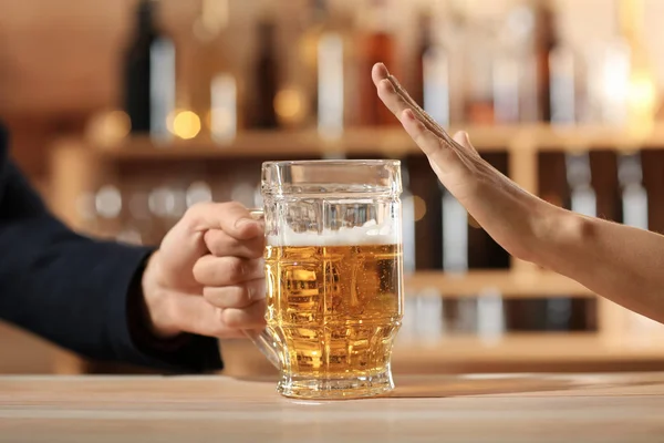 Man with mug of beer and woman refusing to drink in bar
