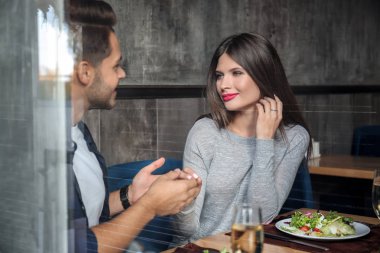 Sevgi dolu çift romantik tarihte Restoran masada oturan camdan görüntülemek