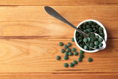 Kase ve ahşap masa spirulina tablet kaşıkla
