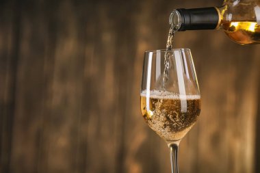 Bir şişe beyaz şarap koyu arka plan üzerinde cam içine dökme