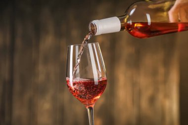 Bir şişe kırmızı şarap cam içine koyu arka plan üzerine dökülen