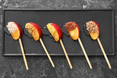 Şeker elma dilimleri plaka üzerinde sopalarla