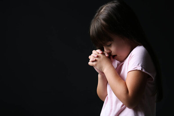 Portrait of praying girl on dark background