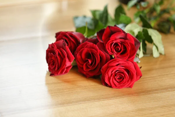 木桌上的美丽红玫瑰花束 — 图库照片