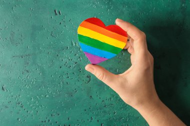 Lgbt gökkuşağı kalp şeklinde boyama renk arka plan üzerinde tutan kadın