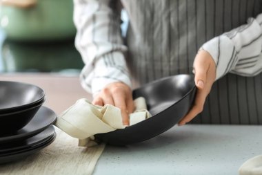 Kadın mutfakta tabak havlu ile silinerek