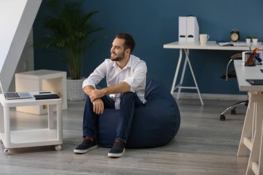 Ofiste beanbag sandalye üzerinde oturan genç işadamı