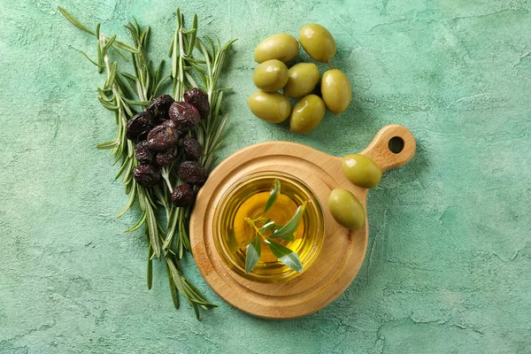 Bowl with fresh oil and olives on color table