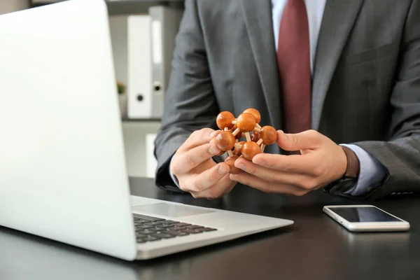 Young businessman with brain teaser at table in office