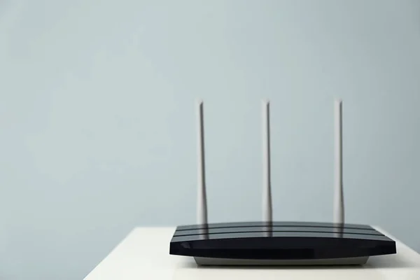 Modern wi-fi router on light table against light background