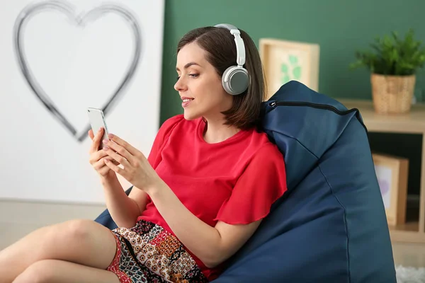 Junge Frau Mit Kopfhörer Und Handy Sitzt Hause Auf Sitzsack — Stockfoto