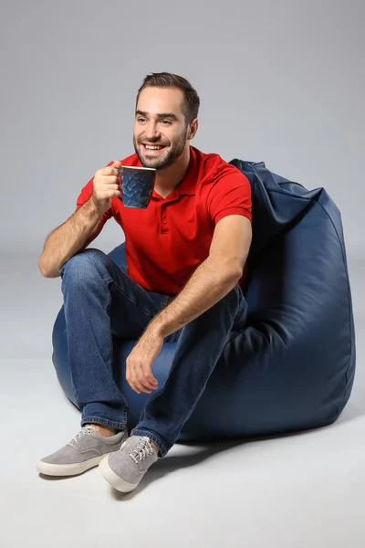 Jovem Com Xícara Chá Sentado Cadeira Saco Feijão Contra Fundo — Fotografia de Stock