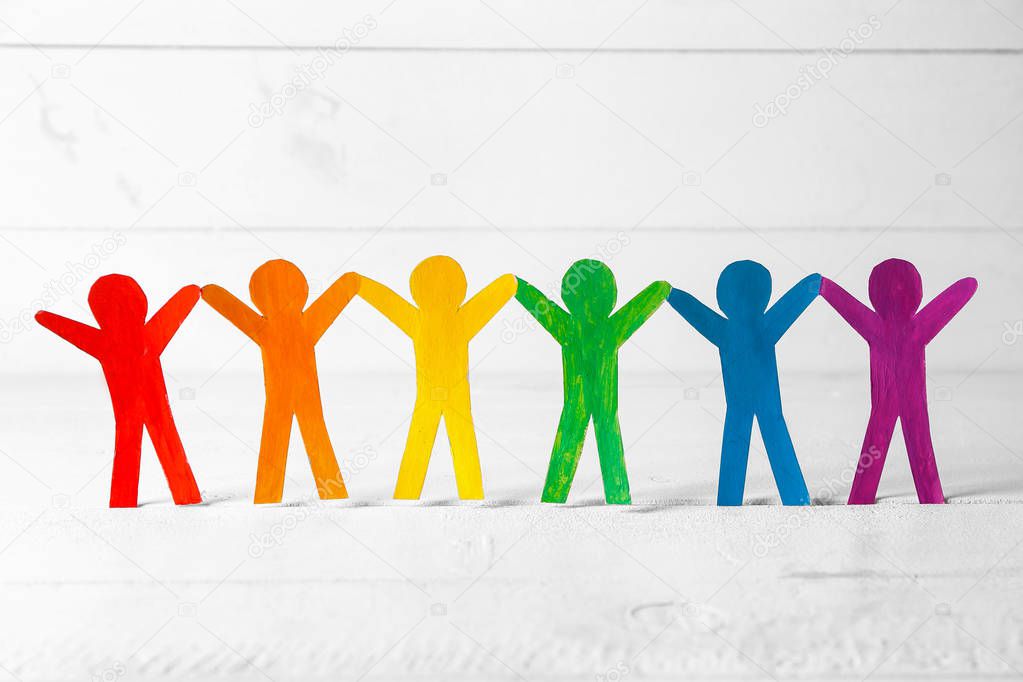 Rainbow paper human figures on white table. LGBT concept