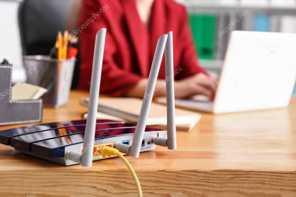 Modern wi-fi router on wooden table in office