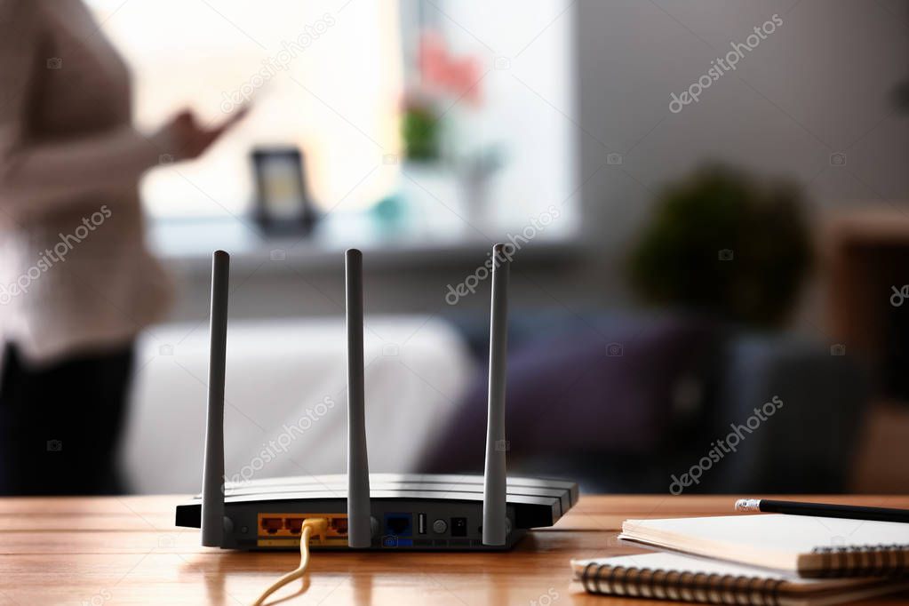 Modern wi-fi router on wooden table in room