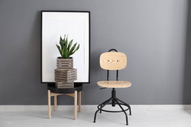 Gri duvarının yakınında masada ahşap kutuları ile dekoratif sansevieria bitki