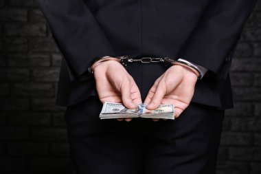 İşadamı ile rüşvet koyu arka plan üzerinde kelepçeli