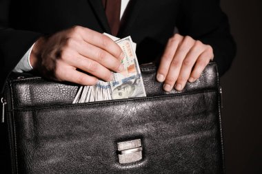 İşadamı doları banknot koyu arka plan üzerinde closeup evrak çantası koyarak. Yolsuzluk kavramı