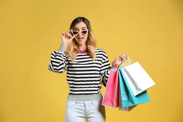 Schöne Junge Frau Mit Einkaufstaschen Auf Farbigem Hintergrund — Stockfoto