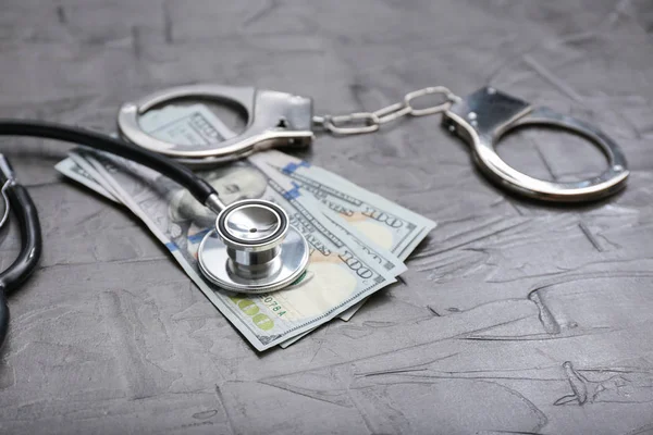 Stethoscope Dollar Banknotes Handcuffs Grey Table Corruption Concept — Stock Photo, Image
