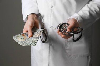 Doktor kelepçeli ve gri arka plan üzerinde rüşvet ile. Yolsuzluk kavramı
