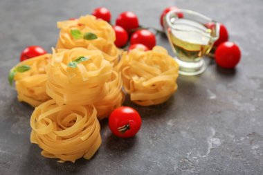 Pişmemiş fettuccine makarna domates gri masada