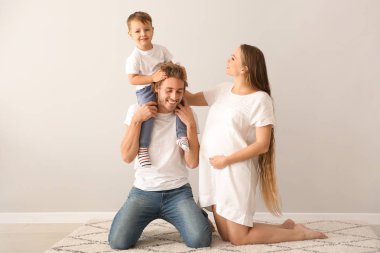 Beyaz duvar yakınındaki halı üzerinde mutlu bir aile portresi