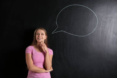Düşünceli genç kadın ve tahtaya çizilen boş konuşma balonu