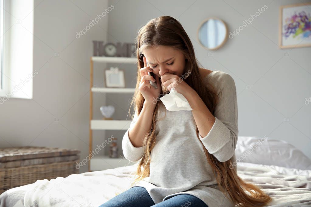 Young pregnant woman talking by phone and crying because of mood change