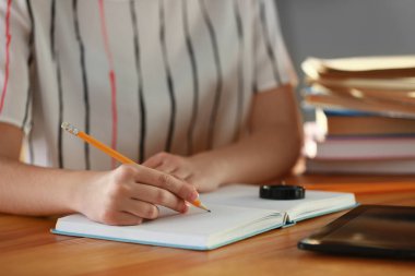 Kadın bir şeyler masada not defterinde yazıyor. Çalışma kavramı