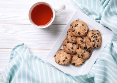 Çikolata parçaları ve çay beyaz ahşap tablo ile lezzetli tatlılar