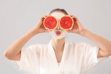 Yüz maskesi ve greyfurt ışık arka plan üzerinde olan güzel kadın