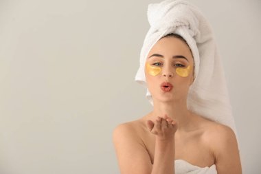 Öpücük ışık arka plan üzerinde üfleme altında göz yamalar ile güzel genç kadın