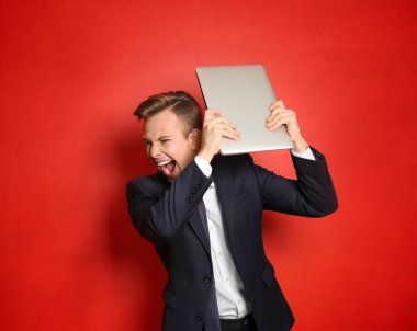 Renk arka plan üstünde laptop ile agresif genç işadamı portresi