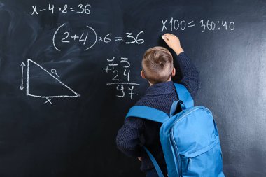 Sınıfta tahtaya yazı yazan şirin bir okul çocuğu.