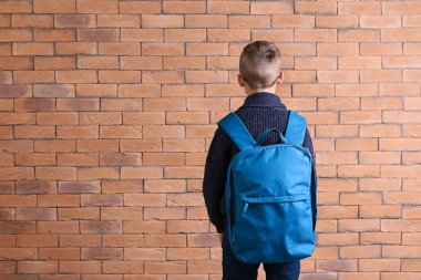 Duvara karşı sırt çantası ile şirin küçük öğrenci