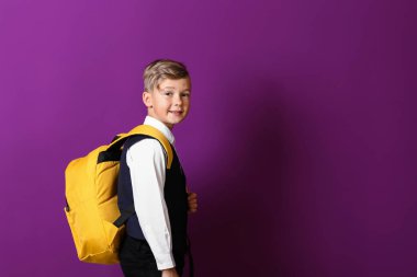 Renk arka plan üzerinde sırt çantası ile şirin küçük öğrenci