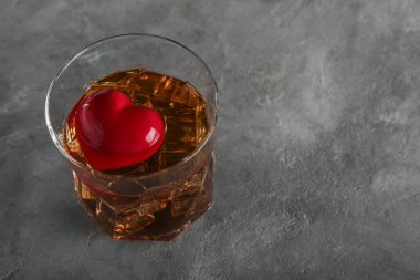 Bir bardak viski gri arka plan üzerinde kalp ile. Alkolizm kavramı