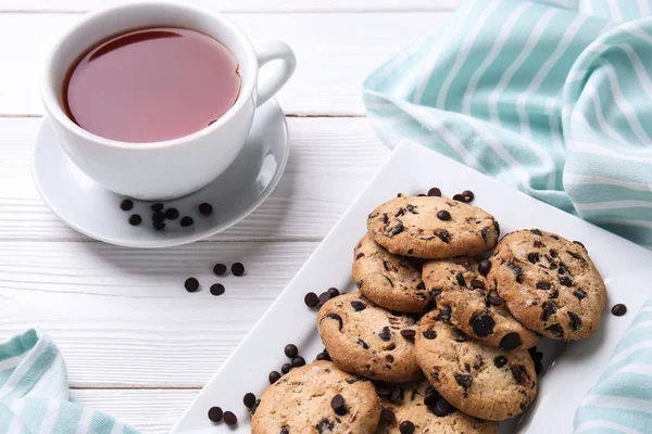 Çikolata parçaları ve çay beyaz ahşap tablo ile lezzetli tatlılar