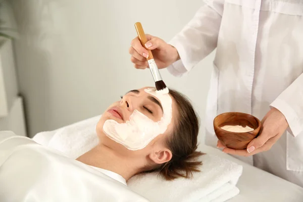 Cosmetologist Aplicando Máscara Rosto Jovem Mulher Salão Beleza — Fotografia de Stock
