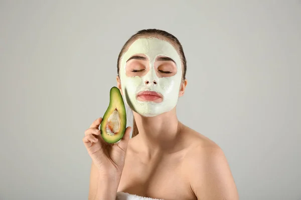 Mooie Jonge Vrouw Met Avocado Gezichtsmasker Lichte Achtergrond — Stockfoto